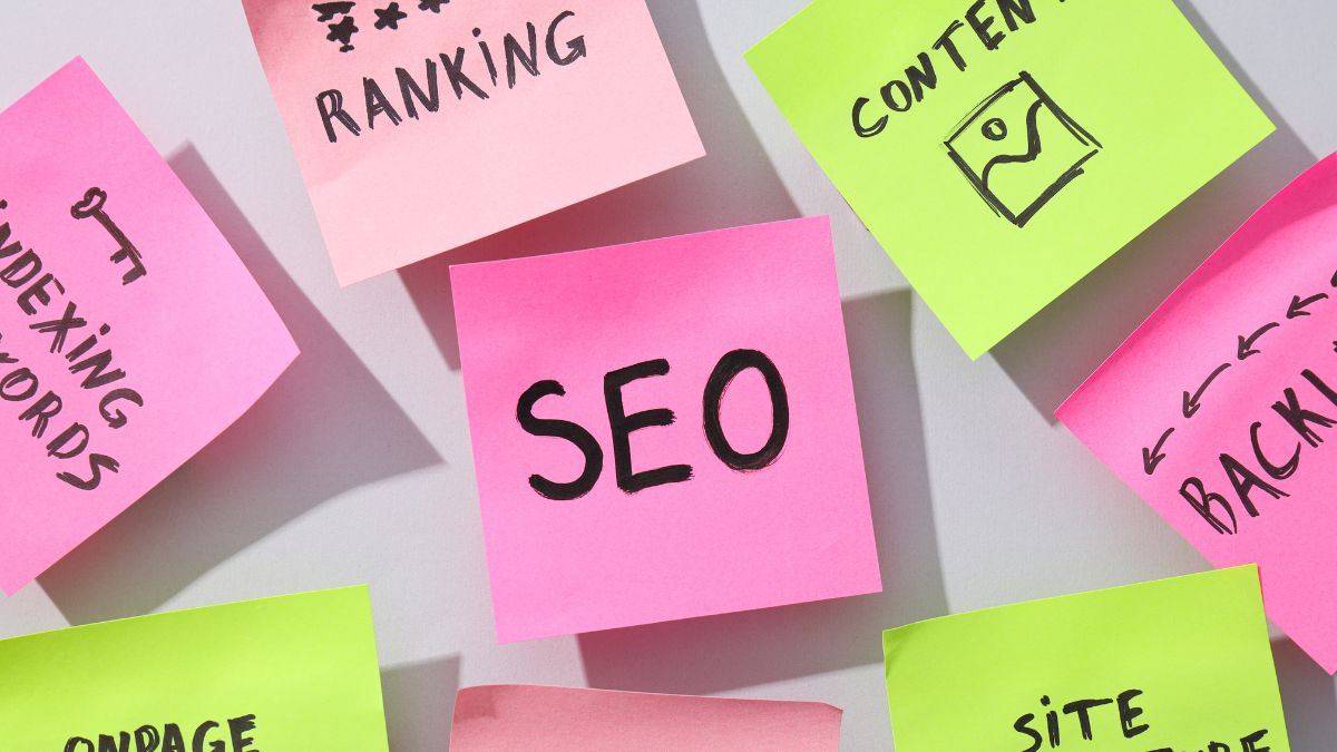Close-up of colourful sticky notes on a desk, including a pink note with “SEO” written in bold black letters, surrounded by notes labelled “ranking,” “content,” and “backlinks.”